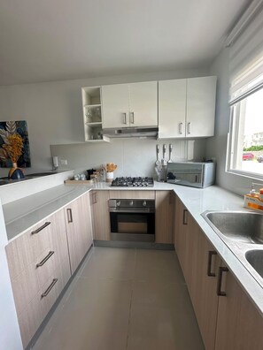 Una cocina moderna con armarios blancos, una estufa a gas y un horno empotrado.