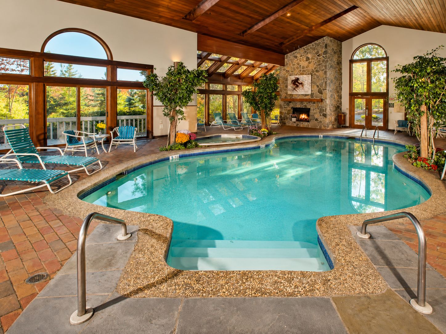 A pool area with a stone wall, lounge chairs, and a fire feature.