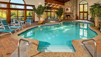 A pool area with a stone wall, lounge chairs, and a fire feature.