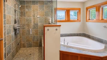 A bathroom with a shower, a bathtub, and a window.