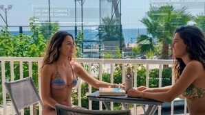 Two individuals seated at an outdoor table with a view of the sea and greenery. - Cambrils-Salou Beach A (Cambrils)
