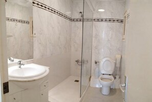 Ein Badezimmer mit Duschkabine, Waschbecken in Weiß und Toilette.