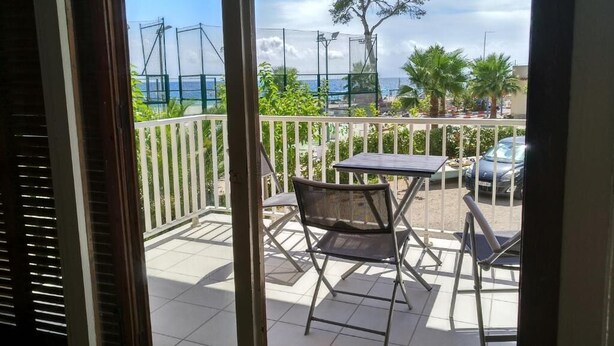 A balcony with a table and chairs, a view of the sea, and a tree. - Cambrils-Salou Beach A (Cambrils)