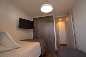 A small, single-room accommodation with a bed, a television mounted on the wall, and a door leading to a hallway. - Andes view - A/C, pool, BBQ grill & free parking (Providencia)