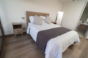Une chambre d’hôtel comprenant un lit, des tables de chevet, un miroir et une armoire.