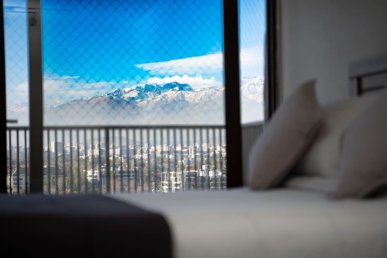 A hotel room with a large window overlooking a cityscape and mountains.