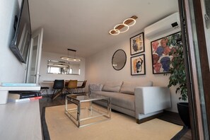 A modern living room with a sofa, coffee table, and dining area. - Andes view - A/C, pool, BBQ grill & free parking (Providencia)