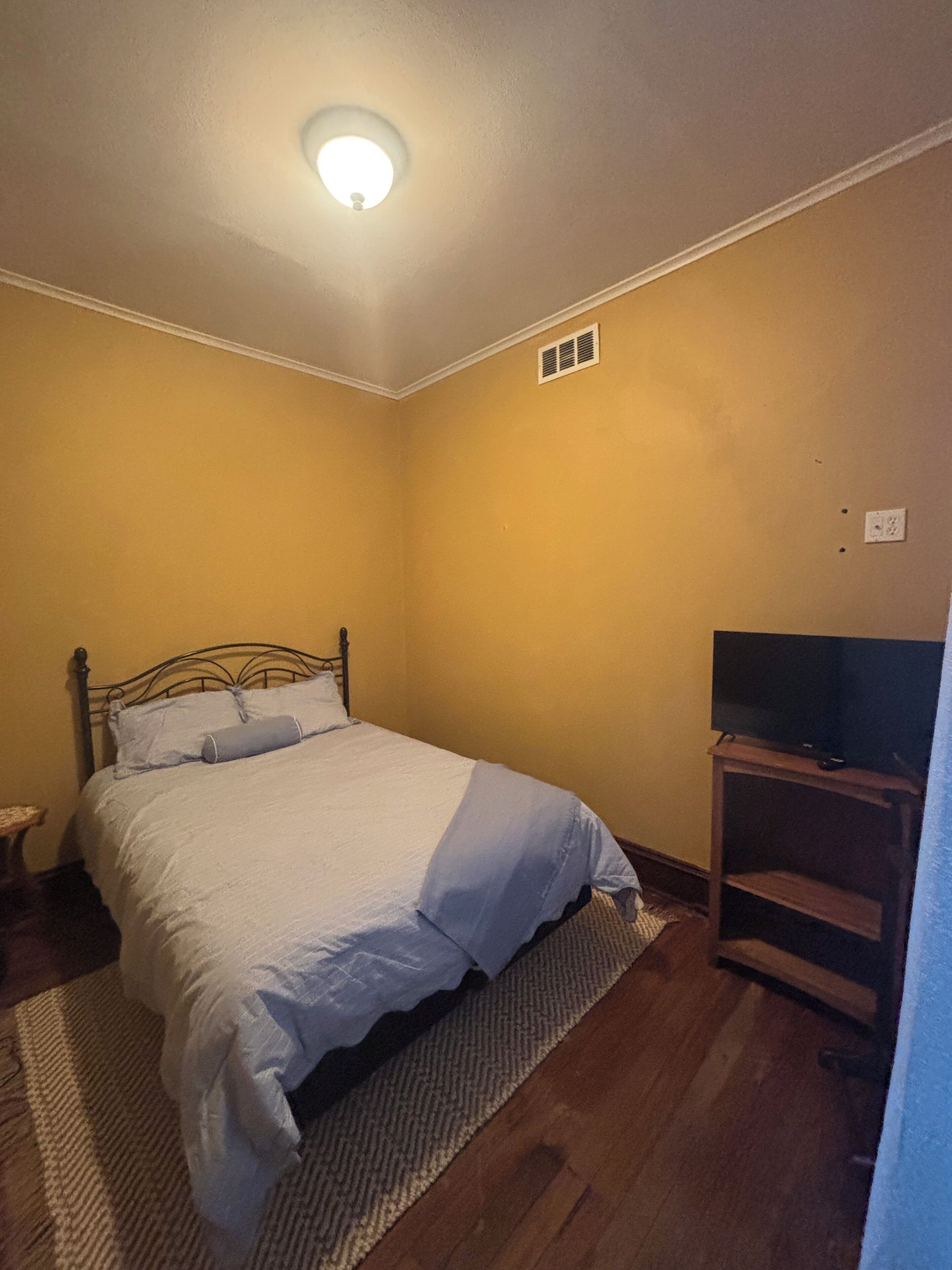 A bedroom with a bed, a television, and a small table.