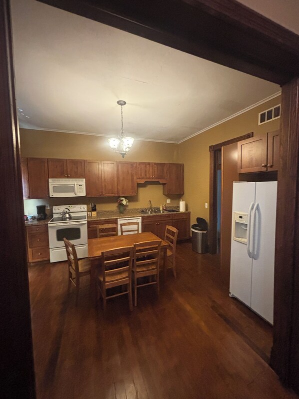 A kitchen with wooden cabinets, a white refrigerator, a stove, and a dining table with chairs.