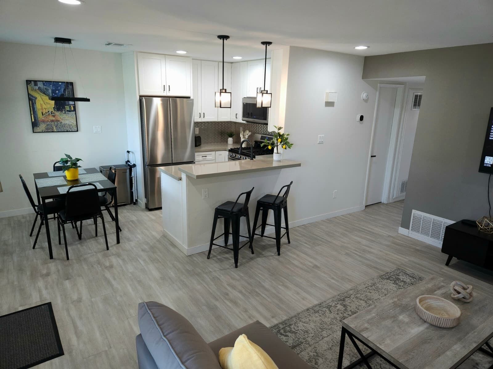 A modern kitchen with a central island, bar stools, and a dining area with a table and chairs.