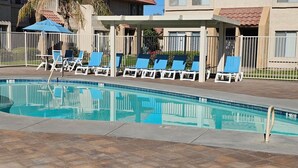 Une piscine avec des chaises longues et des parasols.