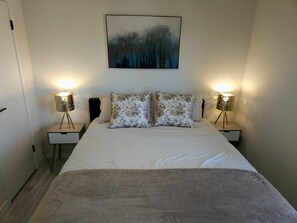 A bedroom with a bed, two nightstands, two lamps, and a painting on the wall. - Luxe & Vibes- Festivals • Golf • Tennis (Indio)