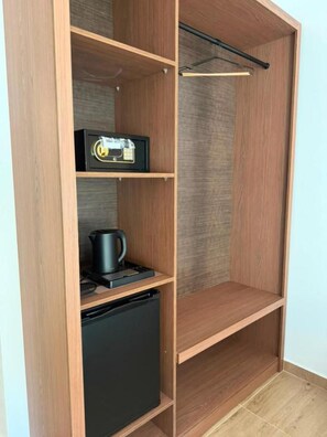 A wooden wardrobe with multiple shelves, a hanging rod, and a small black appliance. - Queen Palace Luxury Hotel (Sarandë)