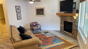 A living room with a leather sofa, a coffee table, a fireplace, a television, and a ceiling fan. - Charming 1-bedroom condo nestled in the mountains of Heavenly Ski Resort (Stateline)