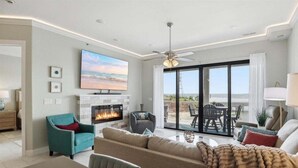 A living room with a fireplace, a ceiling fan, and a large TV. - Penthouse Main Channel Views, Resort Pools & Boat Slip at Topsider's 19mm (Osage Beach)