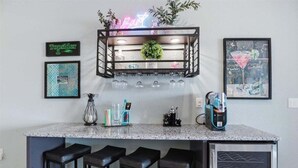 A kitchen with a bar area, including a neon sign, framed artwork, and bar stools. - Penthouse Main Channel Views, Resort Pools & Boat Slip at Topsider's 19mm (Osage Beach)