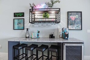 A kitchen with a bar area, including a neon sign, framed artwork, and bar stools. - Penthouse Main Channel Views, Resort Pools & Boat Slip at Topsider's 19mm (Osage Beach)