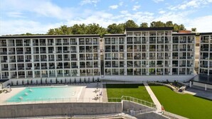 A multi-story hotel with a swimming pool, outdoor seating, and a well-maintained lawn. - Penthouse Main Channel Views, Resort Pools & Boat Slip at Topsider's 19mm (Osage Beach)