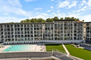 A multi-story hotel with a swimming pool, outdoor seating, and a well-maintained lawn. - Penthouse Main Channel Views, Resort Pools & Boat Slip at Topsider's 19mm (Osage Beach)