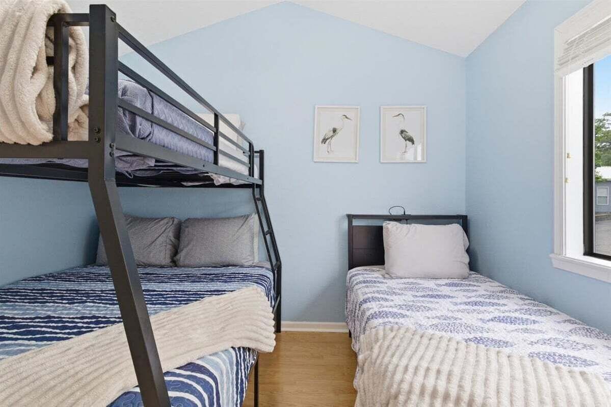 Une pièce avec des lits superposés, une fenêtre et deux tableaux encadrés accrochés au mur.