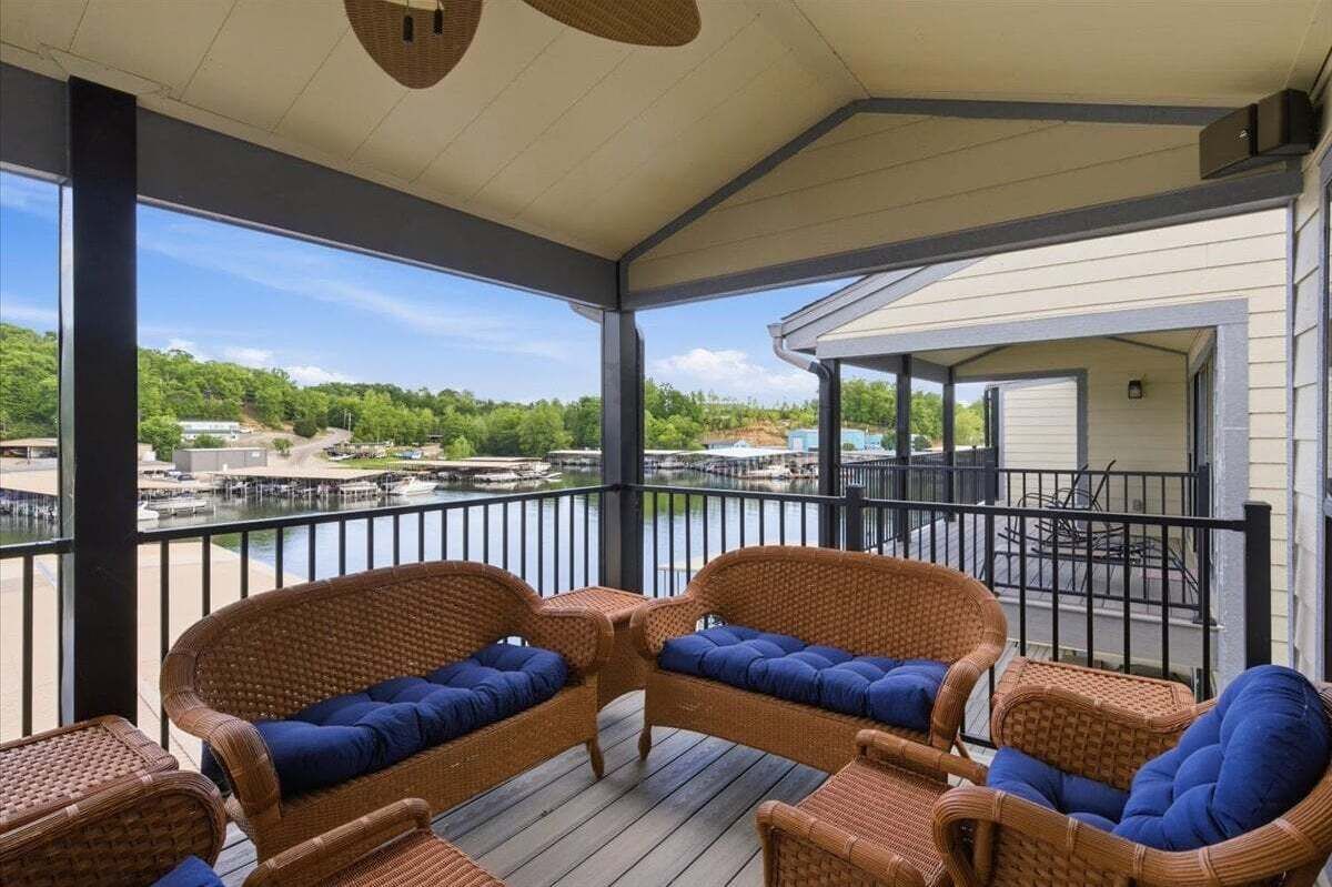 A covered deck with wicker furniture and a view of a marina.
