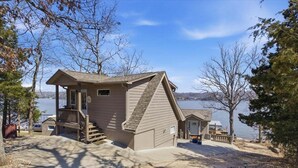 A cabin with a porch, a staircase, and a view of the lake. - Zero-step Dock Life With Big Views, Lake Toys, Firepit, Boat Slip at 43mm (Roach)