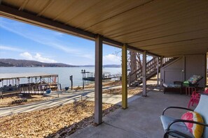 A covered outdoor area with a view of a lake, a dock, and a staircase leading to an upper level. - Zero-step Dock Life With Big Views, Lake Toys, Firepit, Boat Slip at 43mm (Roach)