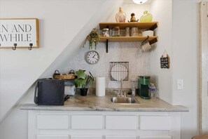 A kitchen with a marble countertop, white cabinetry, a clock, shelves with decorative items, and a sign on the wall. - Zero-step Dock Life With Big Views, Lake Toys, Firepit, Boat Slip at 43mm (Roach)