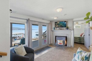 Una sala de estar con chimenea, televisión y vista a la playa.