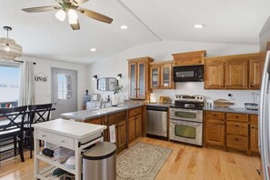 A kitchen with wooden cabinets, a stainless steel refrigerator, and a ceiling fan. - Zero-step Dock Life With Big Views, Lake Toys, Firepit, Boat Slip at 43mm (Roach)