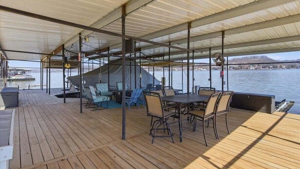 A covered outdoor deck with a table and chairs, a covered seating area, and a view of the water. - Zero-step Dock Life With Big Views, Lake Toys, Firepit, Boat Slip at 43mm (Roach)