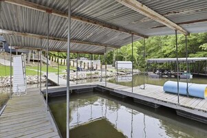Un muelle techado con techo metálico, un muelle de madera y una pequeña masa de agua.