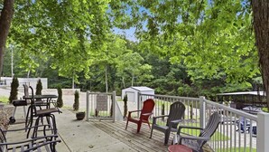 Eine Terrasse mit Sitzgelegenheiten im Freien, eine kleine Gartenhütte und ein weißer Zaun.