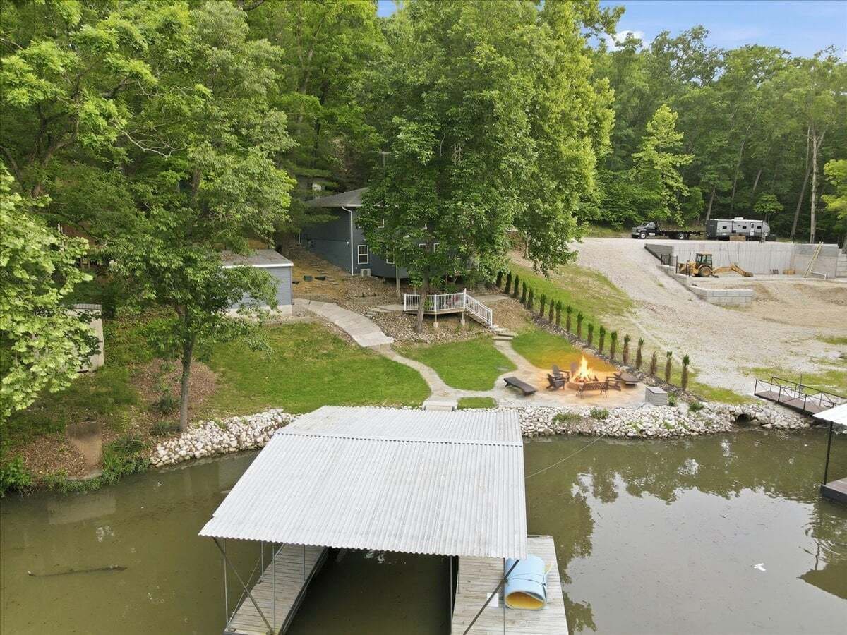 Una propiedad junto al río con un muelle, una zona de fogata y una pequeña construcción.