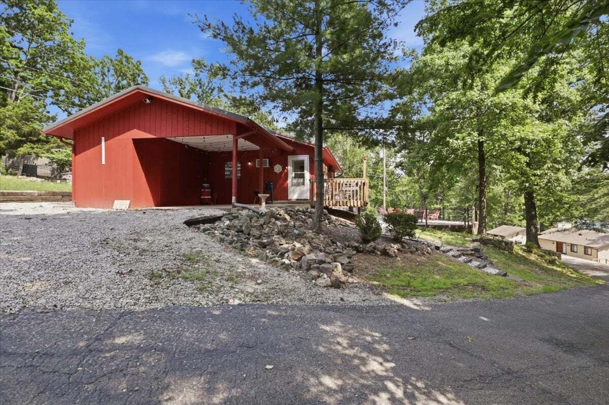 A red building with a covered porch, a small garden with rocks, and a wooden deck.
