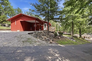 A red building with a covered porch, a small garden with rocks, and a wooden deck.