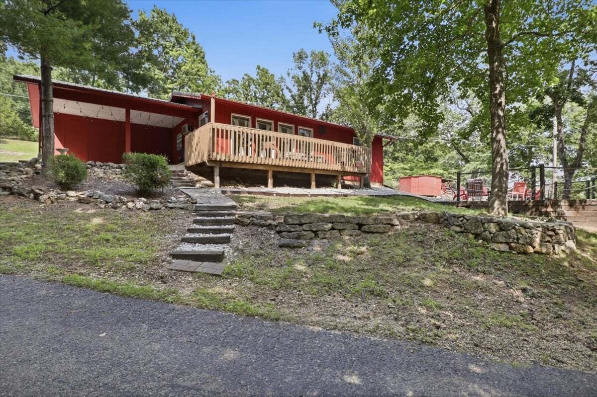 Un bâtiment rouge doté d’une terrasse en bois et d’un escalier en pierre menant à un porche.