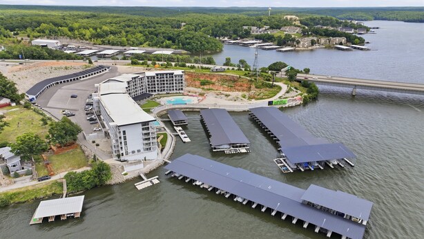 A riverside hotel with multiple docked boats, a swimming pool, and a large building with a curved roof. - Main Channel Views, Resort Pools & Boat Slip at Topsider's 19mm (Osage Beach)
