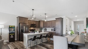 A modern kitchen with a central island, bar stools, and a retro gaming console. - Main Channel Views, Resort Pools & Boat Slip at Topsider's 19mm (Osage Beach)