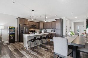 A modern kitchen with a central island, bar stools, and a retro gaming console. - Main Channel Views, Resort Pools & Boat Slip at Topsider's 19mm (Osage Beach)