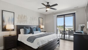 A modern bedroom with a large bed, two bedside tables with lamps, a ceiling fan, and a view through a sliding glass door to an outdoor area. - Main Channel Views, Resort Pools & Boat Slip at Topsider's 19mm (Osage Beach)