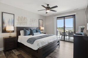 A modern bedroom with a large bed, two bedside tables with lamps, a ceiling fan, and a view through a sliding glass door to an outdoor area. - Main Channel Views, Resort Pools & Boat Slip at Topsider's 19mm (Osage Beach)