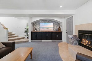 A modern living room with a fireplace, a stone backsplash, and a view of the ocean. - Lakefront Cove Retreat With Private Dock, Slide & Room to Gather (Rocky Mount)