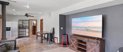 Uma sala de estar moderna com televisão de tela plana, área de jantar e cozinha.