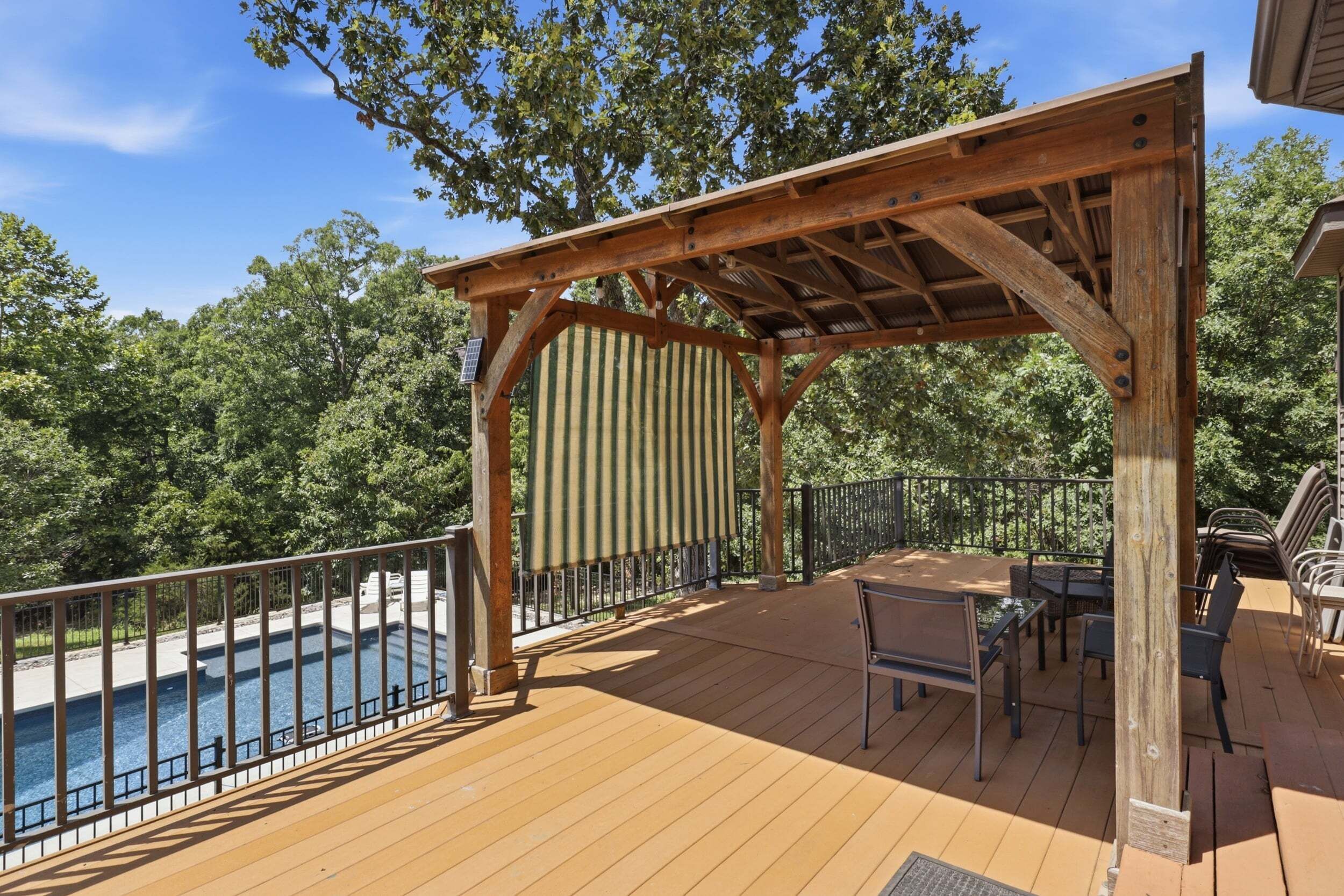 A wooden deck with a pergola, outdoor seating, and a pool.