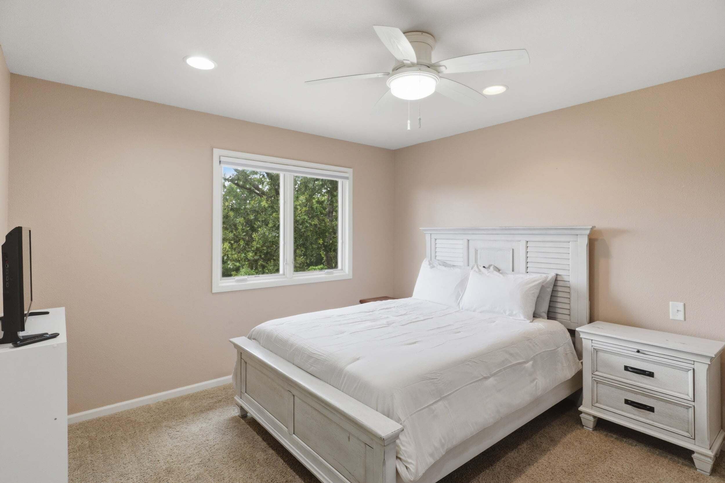 A bedroom with a bed, nightstand, and a ceiling fan.