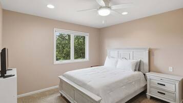 A bedroom with a bed, nightstand, and a ceiling fan.