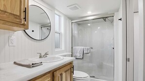 A modern bathroom with a double sink vanity, a toilet, and a glass-enclosed shower.