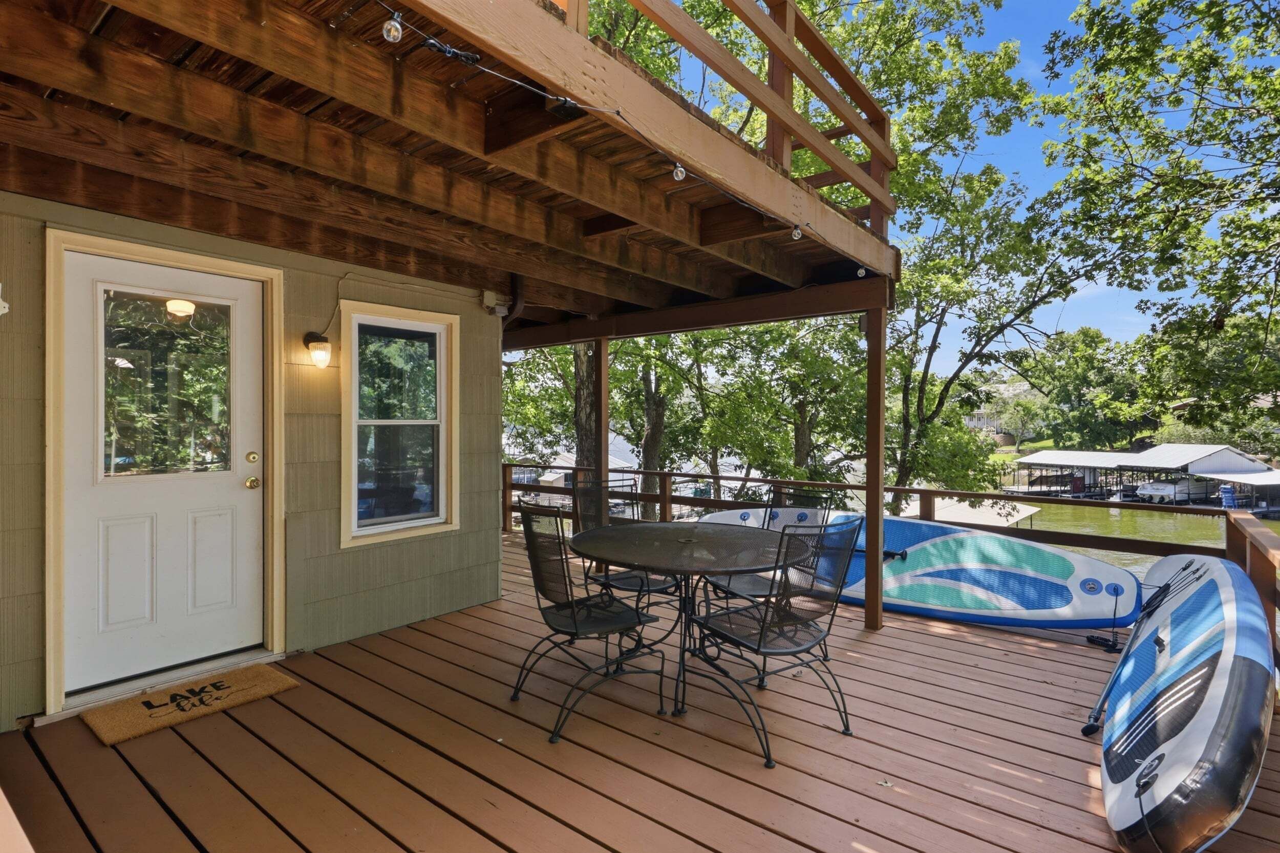 Una terraza de madera con un porche cubierto, una mesa con sillas y un jacuzzi.
