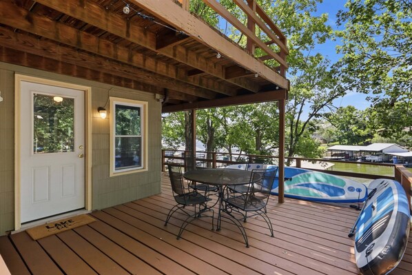 A wooden deck with a covered patio area, a table with chairs, and a hot tub. - Lakefront Escape With Private Dock, Fire Pit & Screened Porch (Barnett)